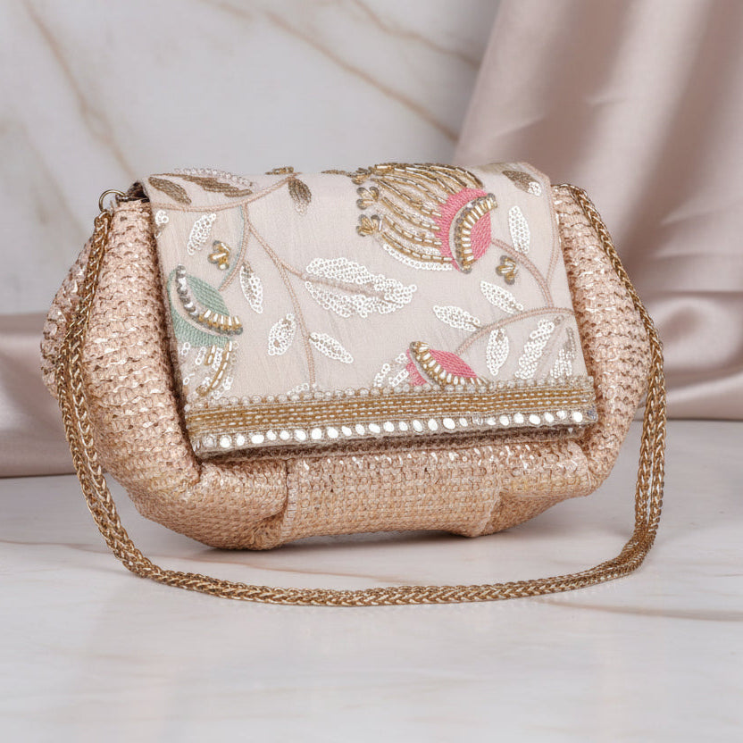 A beige and gold flap clutch with intricate floral and paisley patterns, featuring a flap closure and a chain strap.