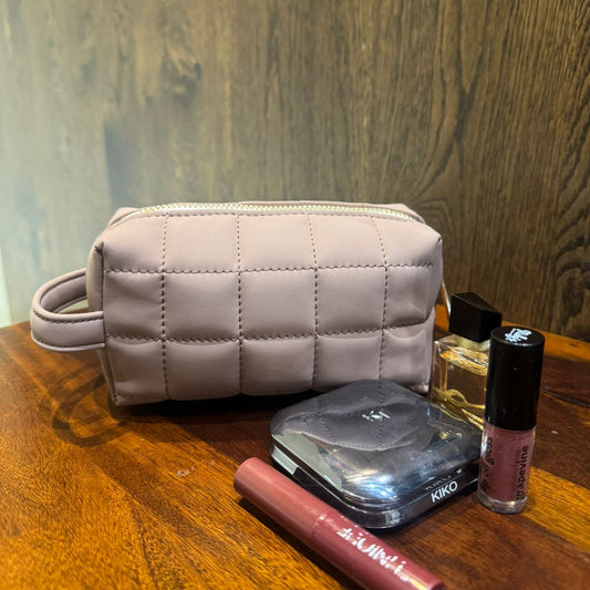 Quilted makeup bag with cosmetic items on a wooden surface
