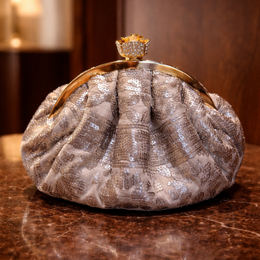 Bronze colored embillished clutch bag with a decorative clasp on a marble surface