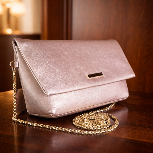 Pink handbag with a gold chain on a wooden surface